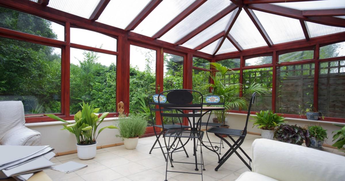 Een nieuw opgeleverde tuinkamer met witte stoelen.